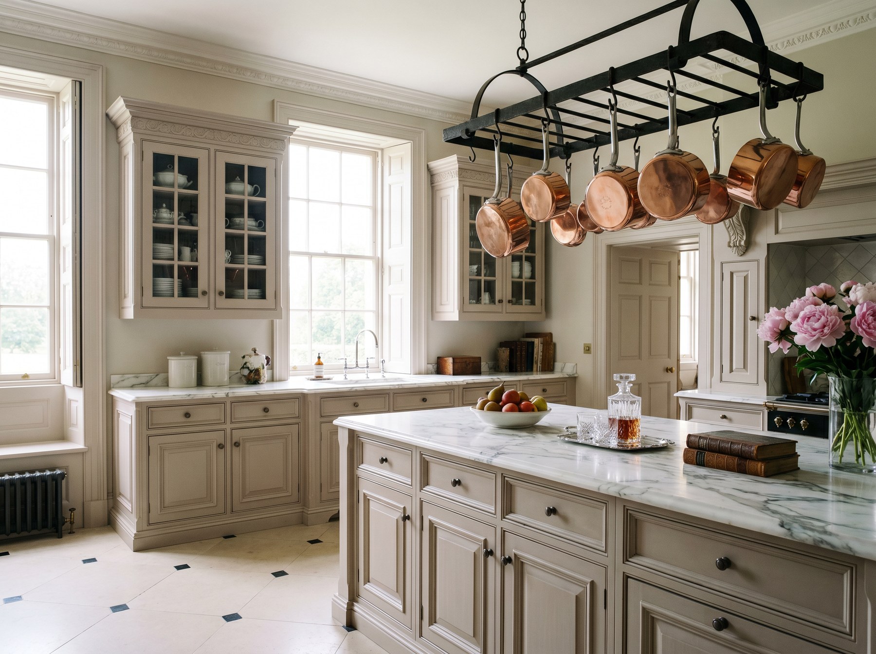 Reeve & Co Essex kitchen in soft mushroom moulded in-frame cabinetry with white Calacatta marble worktops and wrought-iron ceiling pot rack