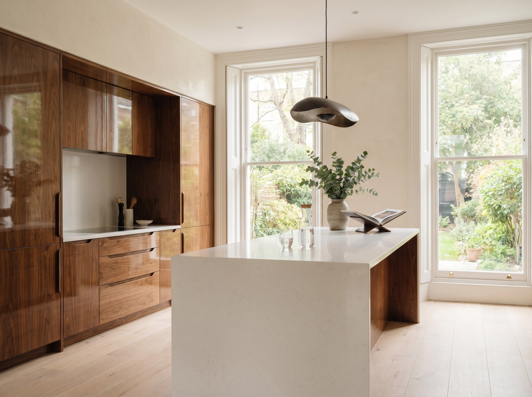 Reeve & Co Kensington kitchen with book-matched walnut veneer handle-less cabinetry, white quartz waterfall island and pale oak floor in a London townhouse