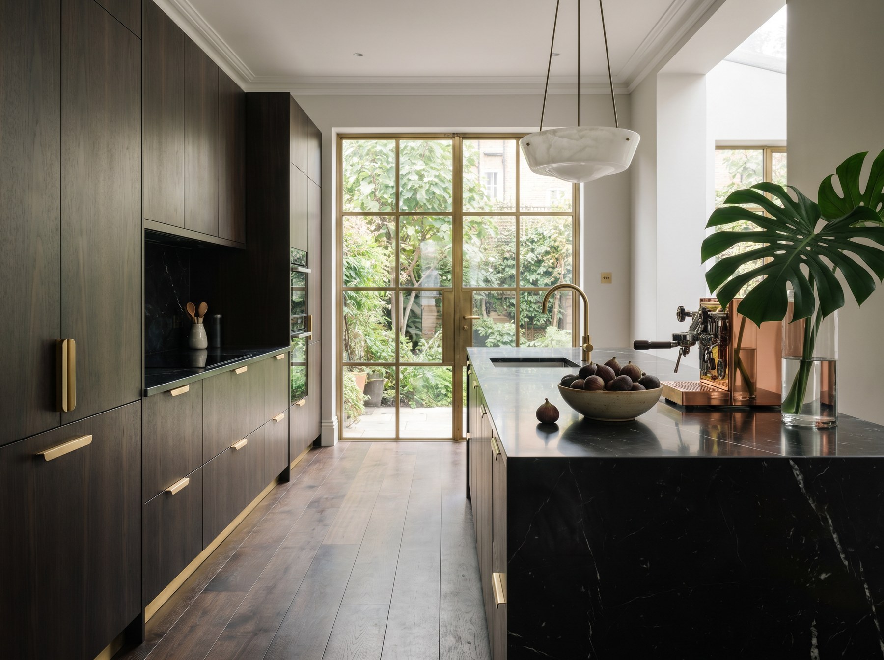 Reeve & Co Kensington kitchen in fumed eucalyptus veneer with handle-less doors, dark stone waterfall island and brushed brass detailing